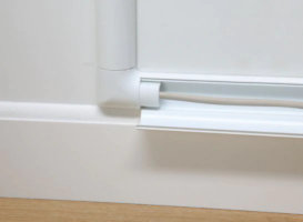 Plastic conduit concealing wires along skirting board