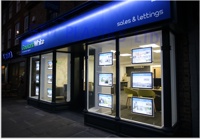 Light pockets in an estate agent window - street view at night-time