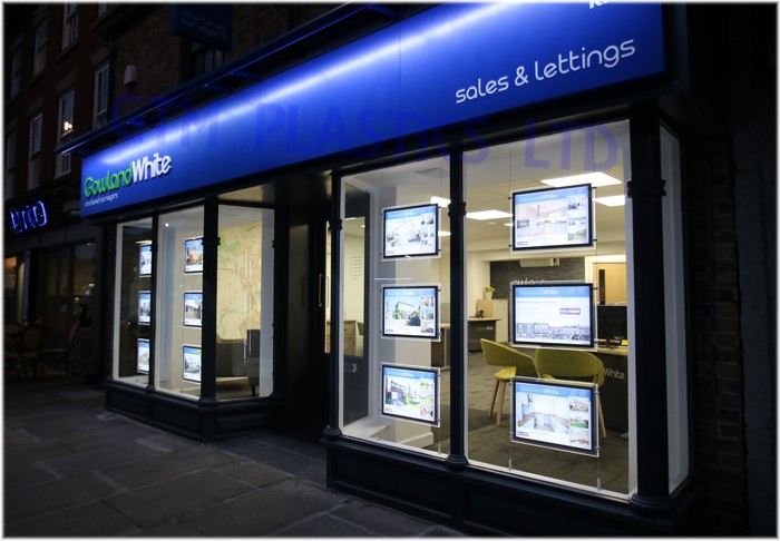 Light pockets in an estate agent window - street view at night-time